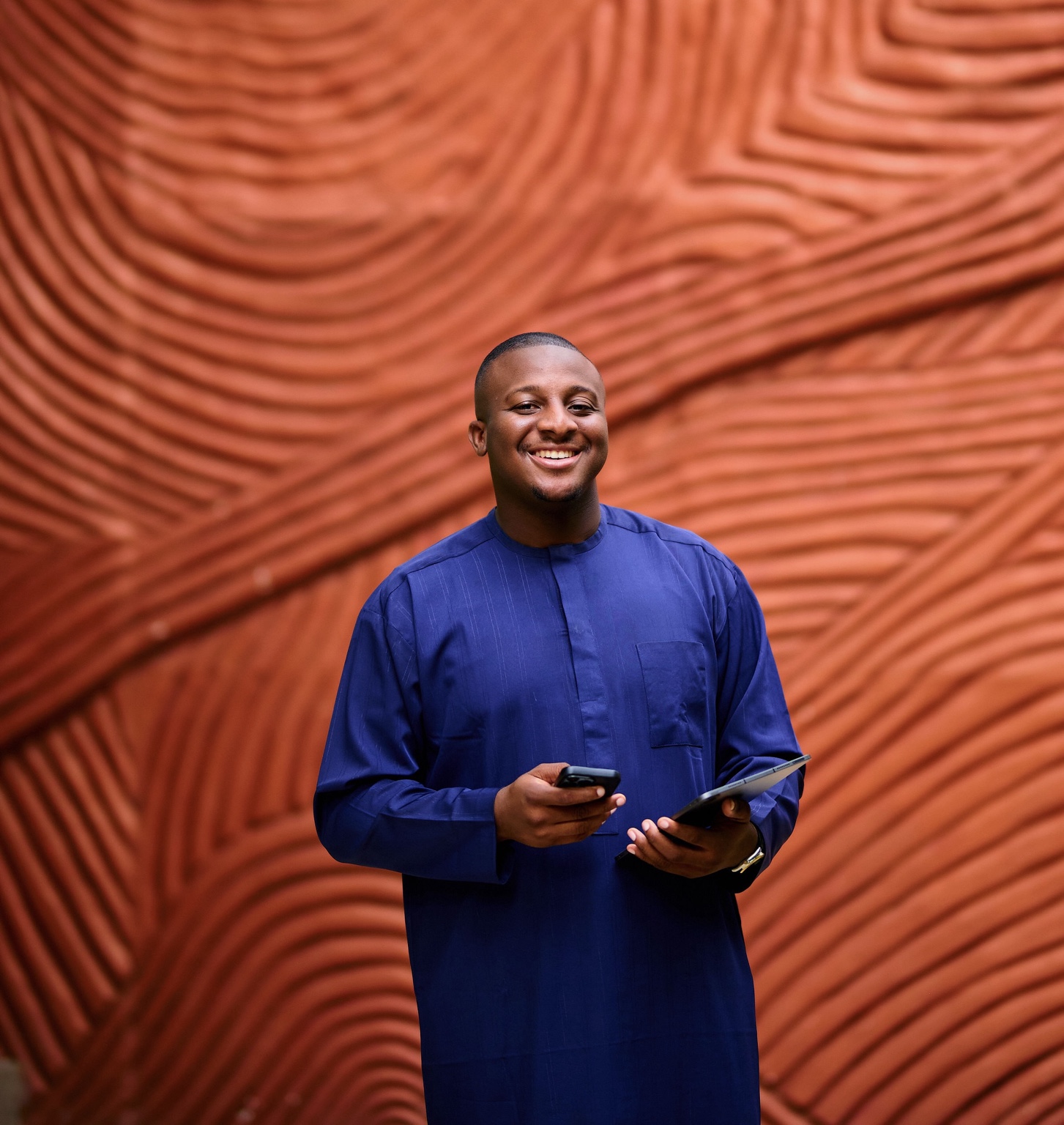 Precious Micah smiling while holding a phone and tablet